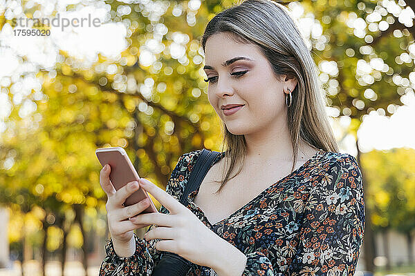 Lächelnde Frau benutzt Smartphone im Park