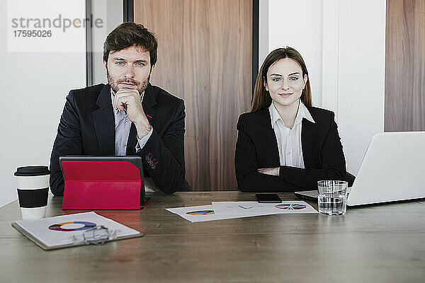 Geschäftskollegen sitzen mit Tablet-PC und Laptop am Schreibtisch im Büro