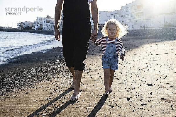 Blonder Junge geht mit Vater am Strand spazieren