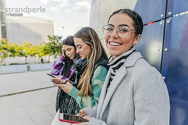 Lächelnde Frau mit Brille steht neben Freunden in der Stadt