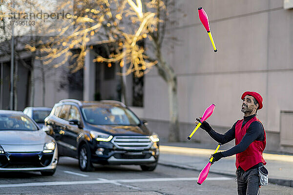 Straßenkünstler jongliert mit Stecknadeln vor Autos