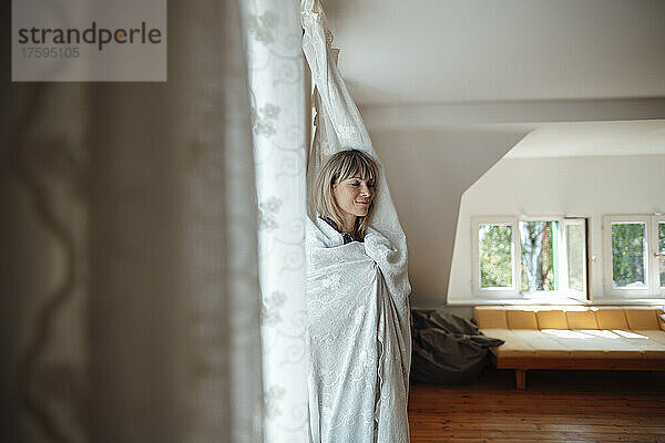Frau mit geschlossenen Augen  zu Hause mit einem Vorhang bedeckt