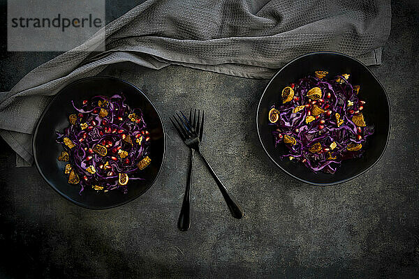 Studioaufnahme von zwei Schüsseln veganem Salat mit Rotkohl  Granatapfelkernen  getrockneten Feigen und Walnüssen