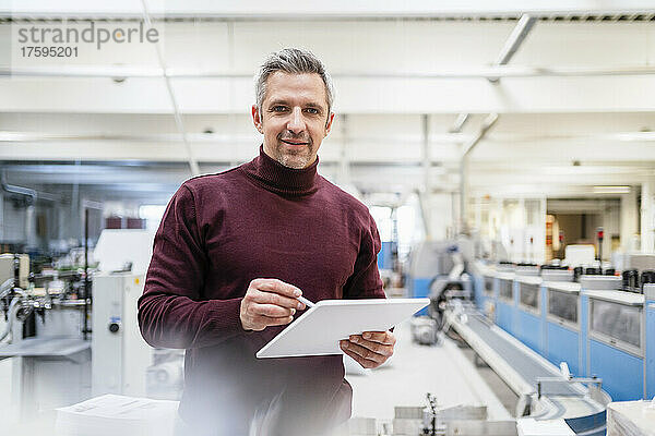 Lächelnder Geschäftsmann mit Tablet-PC in der Industrie