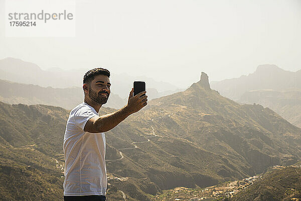 Lächelnder Mann  der in Degollada de Becerra  Spanien  ein Selfie mit dem Mobiltelefon macht