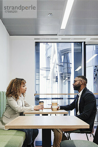 Multiethnische Geschäftskollegen diskutieren bei der Kaffeepause im Coworking-Büro miteinander