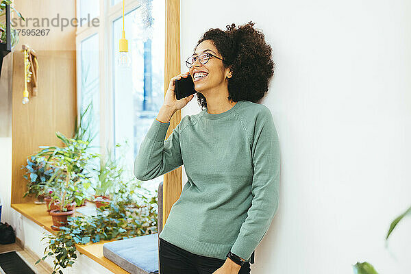 Woman laughing and talking on smart phone at home