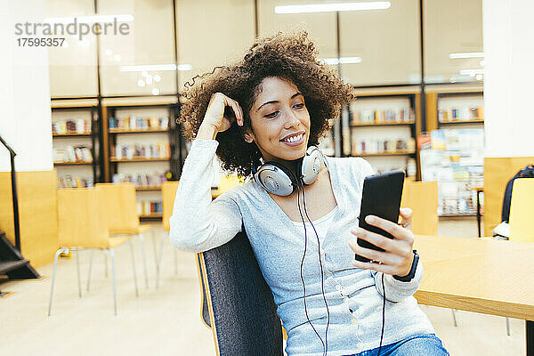 Frau mit Kopfhörern um den Hals und Smartphone
