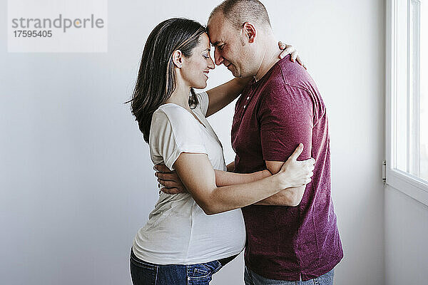 Mann umarmt schwangere Frau zu Hause