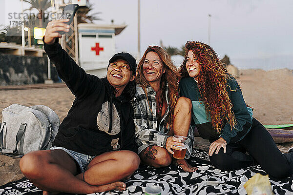 Lächelnde  gemischtrassige Freunde  die am Strand ein Selfie mit dem Smartphone machen