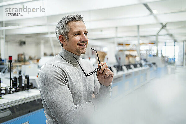 Lächelnder Geschäftsmann mit Brille in der Fabrik