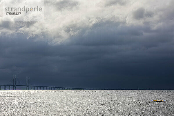 Bewölkter Himmel über der Meerenge mit der Silhouette der Öresundbrücke im Hintergrund