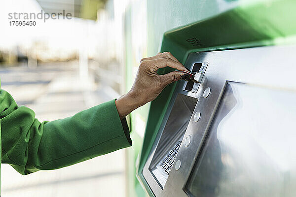 Die Hand einer Geschäftsfrau steckt eine Smartcard in den Fahrkartenautomaten