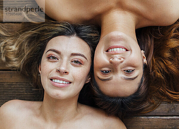 Lächelnde junge Frauen liegen auf Holzboden