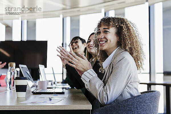 Fröhliche Geschäftskollegen applaudieren bei einem Treffen im Coworking-Büro