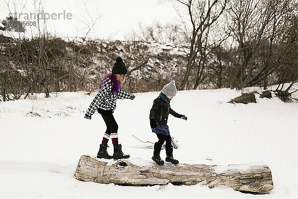 Mädchen laufen im Winter auf Baumstämmen