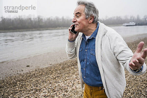 Älterer Mann telefoniert am Strand