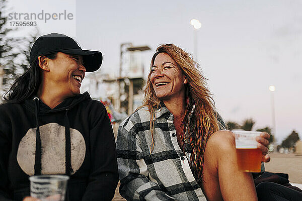 Fröhliche Freunde  die am Strand Bier trinken