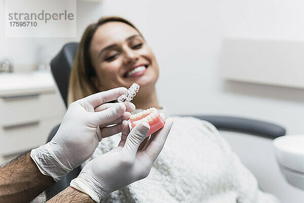 Zahnarzt hält Zahnersatz vom Patienten im Krankenzimmer