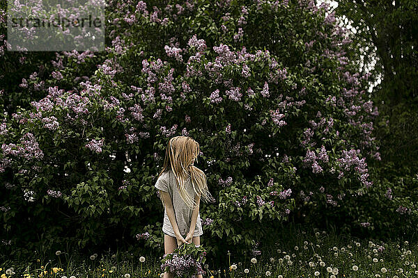 Blondes Mädchen vor frischen Blumen in der Natur