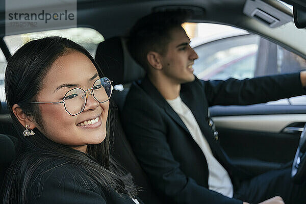 Lächelnde Geschäftsfrau mit Kollege beim Autofahren