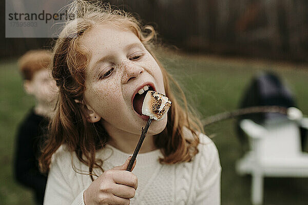 Mädchen isst gerösteten Marshmallow