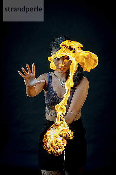Performer playing with fire against black background