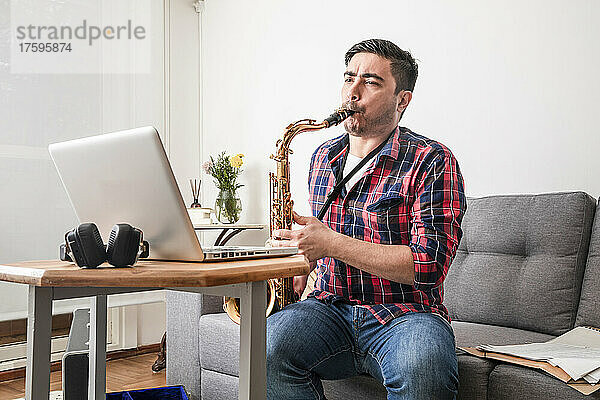 Musiker unterrichtet Saxophon per Videoanruf über Laptop zu Hause