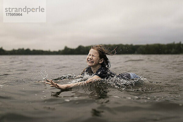 Glückliches Mädchen mit geschlossenen Augen schwimmt im See