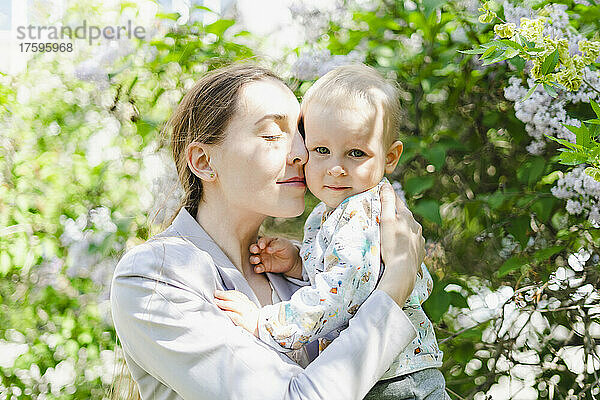 Mutter mit geschlossenen Augen umarmt Sohn im Garten