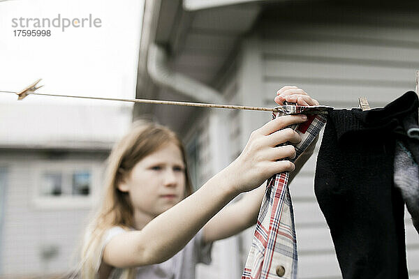 Mädchen hängt Kleidung an Seil