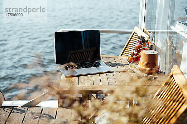 Laptop auf Holztisch am Hausboot an einem sonnigen Tag