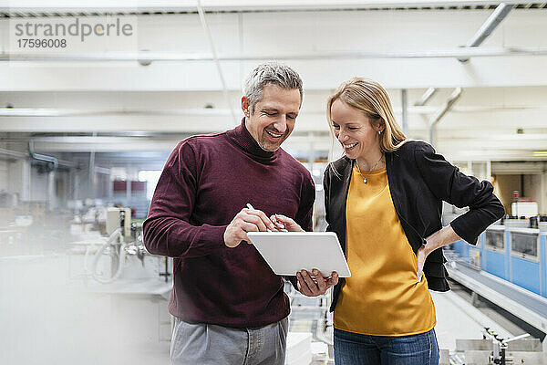 Glückliche Geschäftsfrau und Geschäftsmann  die Tablet-PC in der Industrie teilen
