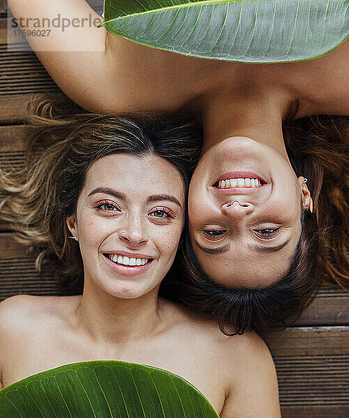 Happy young women lying down with leaves