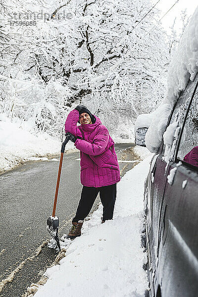 Mann mit Schneeschaufel steht im Winter auf der Straße