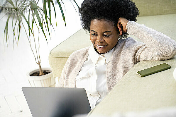 Lächelnde Geschäftsfrau  die im Wohnzimmer am Laptop arbeitet