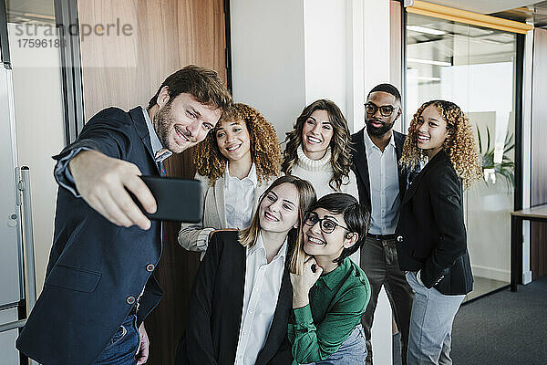 Glückliche Geschäftsleute und Geschäftsfrauen  die im Büro ein Selfie mit dem Mobiltelefon machen