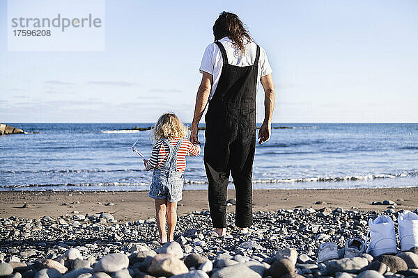 Vater und Sohn halten sich am Strand an den Händen