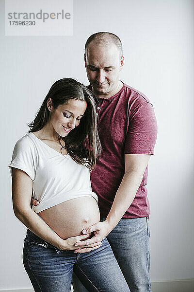 Mann berührt Bauch seiner schwangeren Frau zu Hause