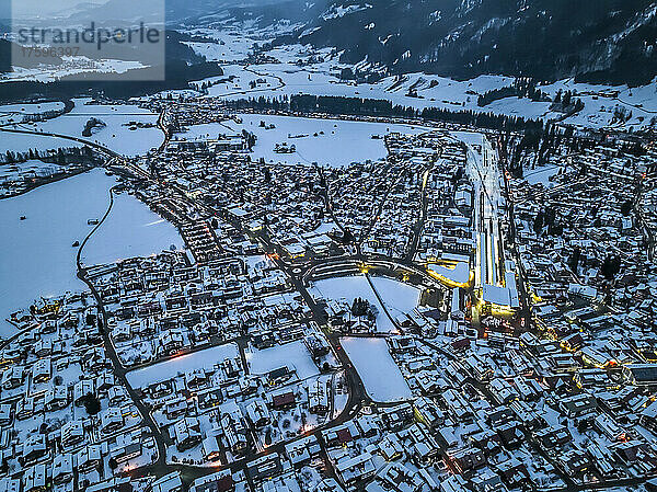 Germany  Bavaria  Oberstdorf  Helicopter view of snow covered town in Allgau Alps at dusk