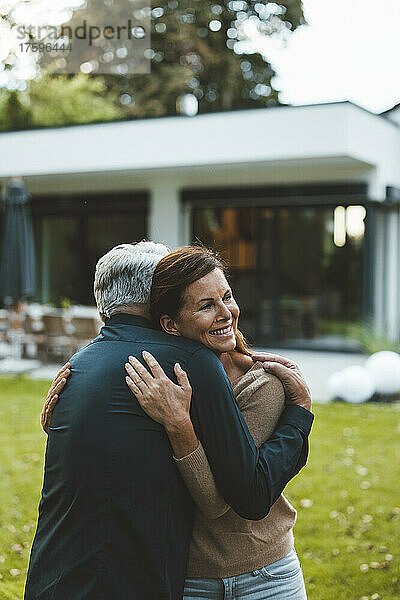 Glückliche Frau umarmt Mann im Hinterhof