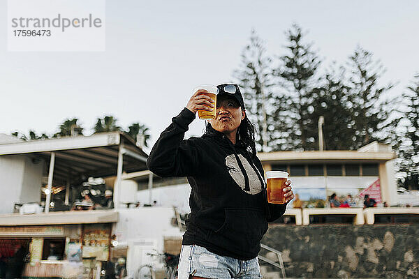 Woman with beer cups standing at beach
