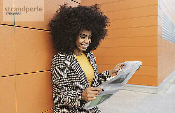 Lächelnde Frau liest Zeitung auf Fußweg