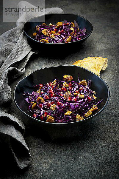 Studioaufnahme von zwei Schüsseln veganem Salat mit Rotkohl  Granatapfelkernen  getrockneten Feigen und Walnüssen