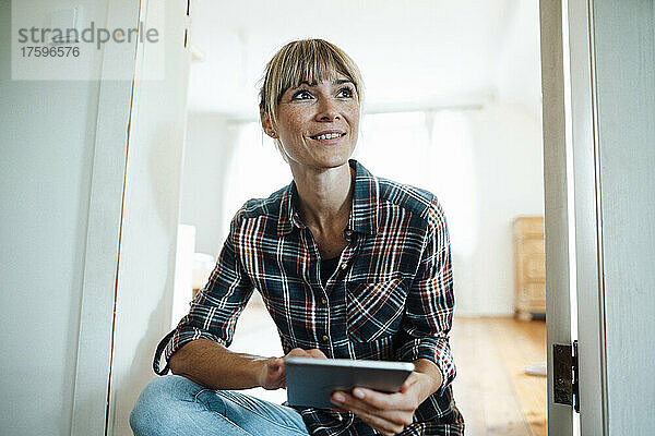 Thoughtful woman with digital tablet at home