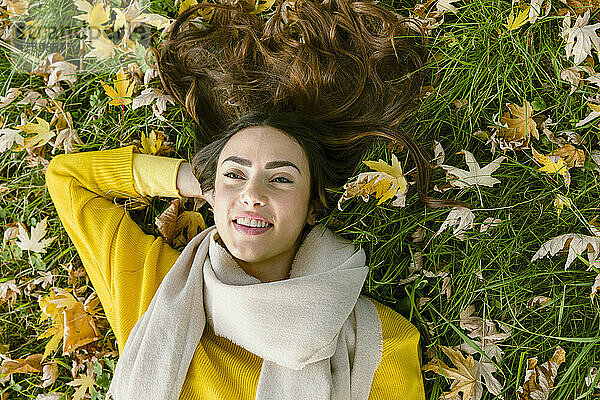Junge Frau liegt auf Gras im Herbstpark