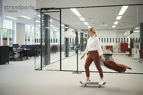 Geschäftsfrau fährt im Büro auf Skateboard