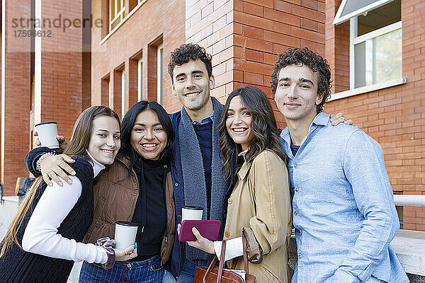 Glückliche gemischtrassige Studenten  die auf dem College-Campus stehen