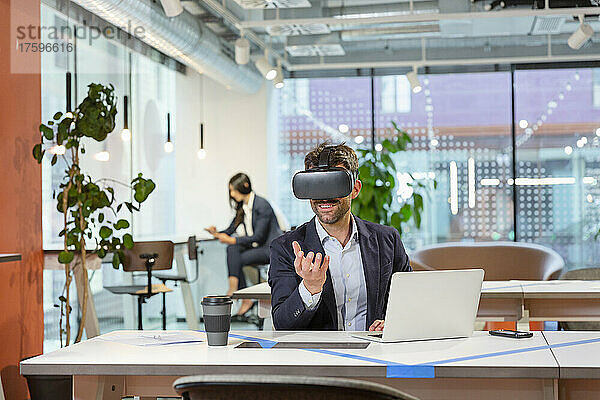 Mitarbeiter mit VR-Brille gestikuliert im Büro