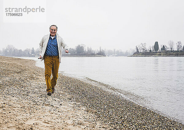 Glücklicher älterer Mann  der am Strand läuft